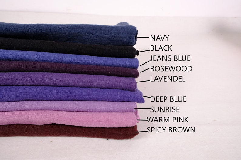 May include: A stack of ten fabric swatches in various shades of blue, purple, pink, and brown. The swatches are labelled with the following colours: Navy, Black, Jeans Blue, Rosewood, Lavendl, Deep Blue, Sunrise, Warm Pink, and Spicy Brown.