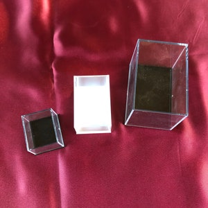 May include: Three clear acrylic display boxes of different sizes. The boxes are empty and have black interiors.