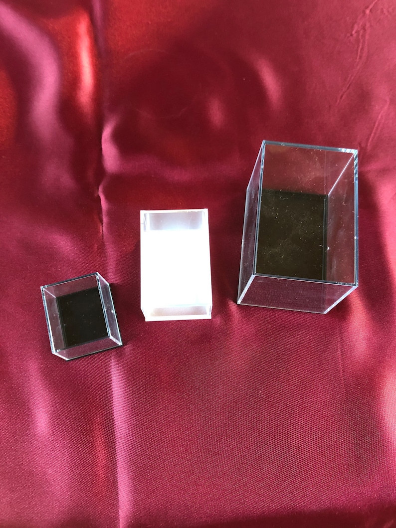 May include: Three clear acrylic display boxes of different sizes. The boxes are empty and have black interiors.