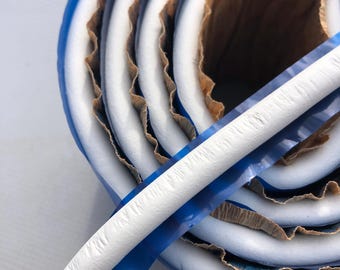 May include: A white foam weather stripping with a blue tape backing. The foam is rolled up and the tape is visible on the outside of the roll.