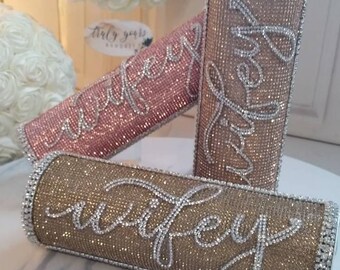 May include: Three sparkly clutches with the word "wifey" spelled out in rhinestones. The clutches are in gold, rose gold, and silver.