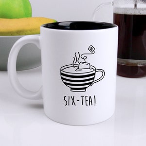 May include: White ceramic mug with a black interior and a black and white illustration of a teacup with a tea bag and steam. The text "SIX-TEA!" is printed below the illustration.