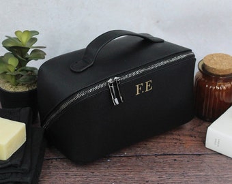 May include: Black leather travel makeup bag with a zip closure and a top handle. The bag has the initials "F.E." embossed on the front.