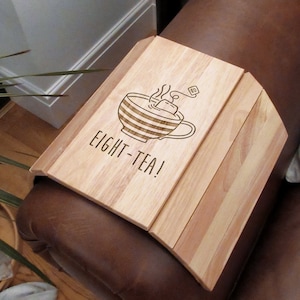 Peut inclure: Un plateau en bois avec un bord incurvé, conçu pour s'adapter à un accoudoir. Le plateau est gravé au laser avec un motif de tasse à thé avec de la vapeur et le texte "Eight-Tea!"
