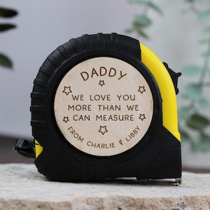 May include: A yellow and black tape measure with a wooden insert that reads "Daddy We love you more than we can measure from Charlie & Libby".
