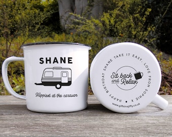 May include: White enamel camping mug with a black handle and black text that reads "SHANE Happiest at the caravan" and a black silhouette of a camper. The back of the mug has black text that reads "HAPPY BIRTHDAY SHANE TAKE IT EASY. LOVE FROM SOPHIE X www.giftsinajiffy.co.uk" and a black silhouette of a mug with steam coming out of it.
