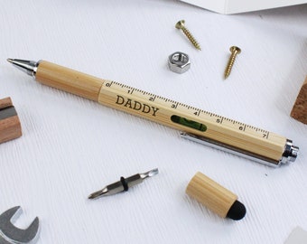 May include: A wooden multi-tool pen with a ruler, level, and screwdriver. The pen is engraved with the word "DADDY".