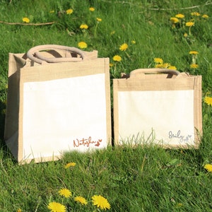 May include: Two natural jute tote bags with white fabric panels. The larger bag has the name "Natasha" written in brown script with two small hearts. The smaller bag has the name "Emily" written in grey script with two small hearts.