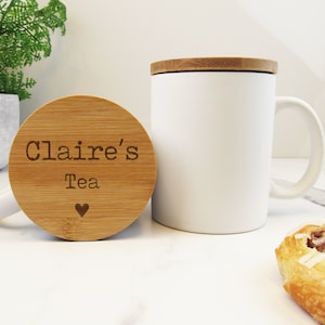 May include: White ceramic mug with a bamboo lid. The lid has the text "Claire's Tea" with a small heart symbol.
