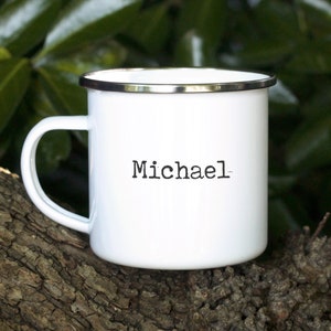 Könnte beinhalten: Weiße Emailtasse mit silbernem Rand und dem Namen "Michael" in Schwarz gedruckt.