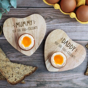 Può includere: Due porta uova di legno a forma di cuore con il testo "Mummy you are egg-cellent!" e "Daddy you are egg-cellent!" Ogni porta uova contiene un uovo sodo.