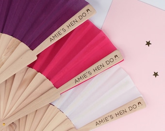May include: Three wooden hand fans with colorful fabric panels. Each fan has a personalized message that reads "Amie's Hen Do" with a small graphic of high heels.