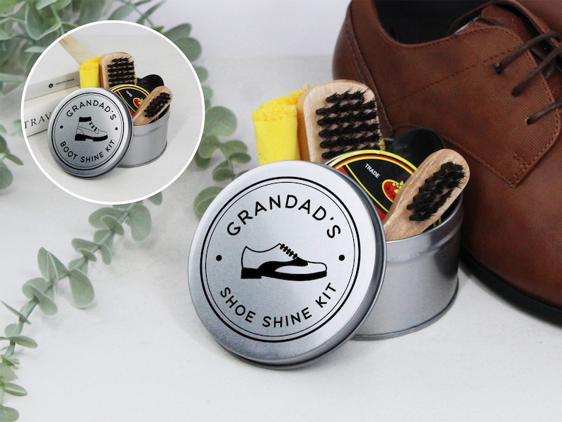 May include: A silver tin with a black and white label that says "Grandad's Shoe Shine Kit" and a picture of a shoe. The tin is filled with shoe polish, brushes, and cloths.