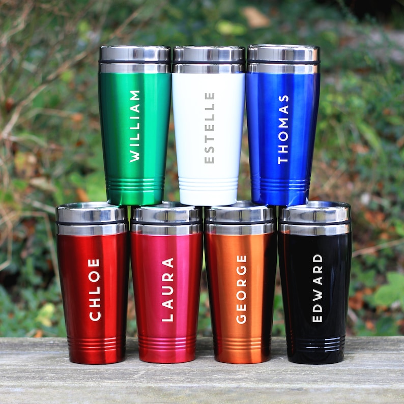 May include: Six personalized travel mugs with names printed on them. The mugs are in different colors: green, white, blue, red, pink, orange, and black.