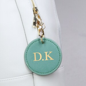 May include: A white bag with a green leather keychain that says "D.K."