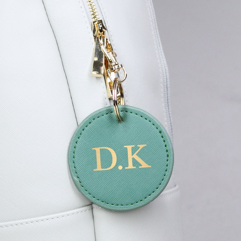 May include: A white bag with a green leather keychain that says "D.K."