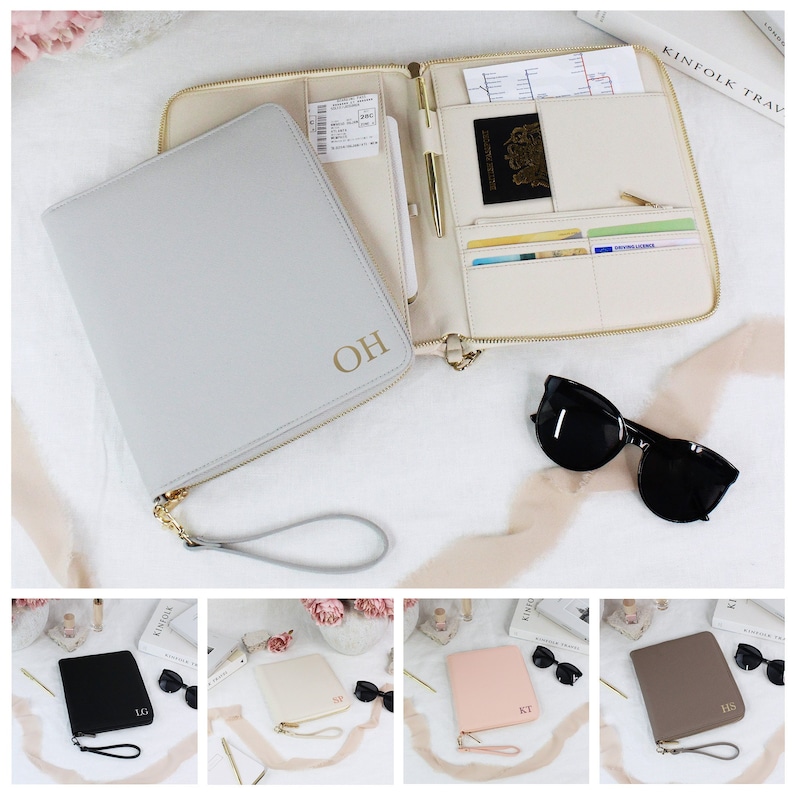 May include: Four personalized travel wallets in different colors: gray, black, cream, and brown. Each wallet has a gold zipper and a gold chain strap. The wallets are monogrammed with the initials "OH", "LG", "SY", "KT", and "HS".