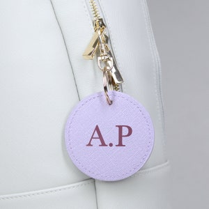 May include: A light purple leather keychain with the initials "A.P." in a darker purple color.