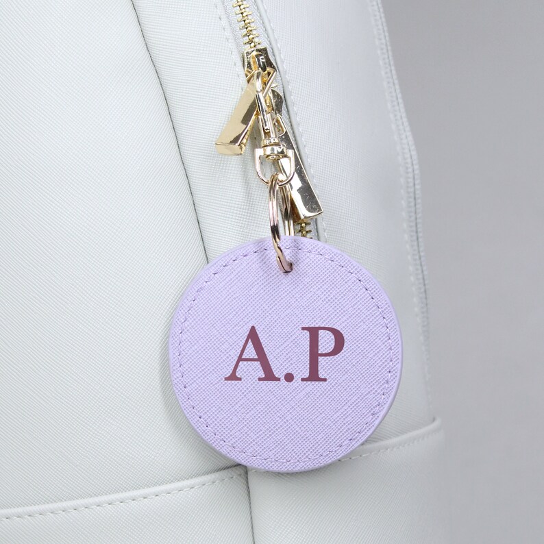 May include: A light purple leather keychain with the initials "A.P." in a darker purple color.