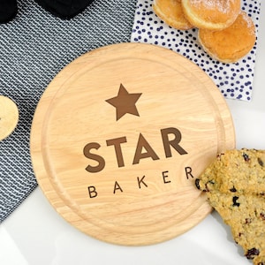 May include: A round wooden cutting board with the words "STAR BAKER" and a star engraved on it.