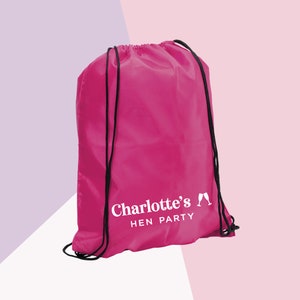 May include: A pink drawstring bag with black drawstrings. The bag has white text that says "Charlotte's" with two champagne glasses and "HEN PARTY".