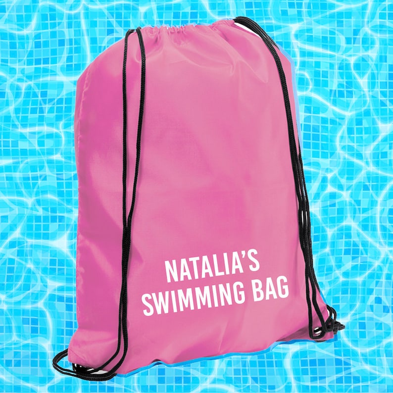 May include: Pink drawstring bag with black drawstrings and the text "Natalia's Swimming Bag" printed in white.