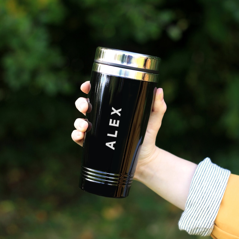 May include: Black travel mug with a silver lid and the name "ALEX" engraved on the side.