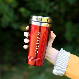 May include: Red travel mug with a silver lid and the name "WILLIAM" engraved on the side.
