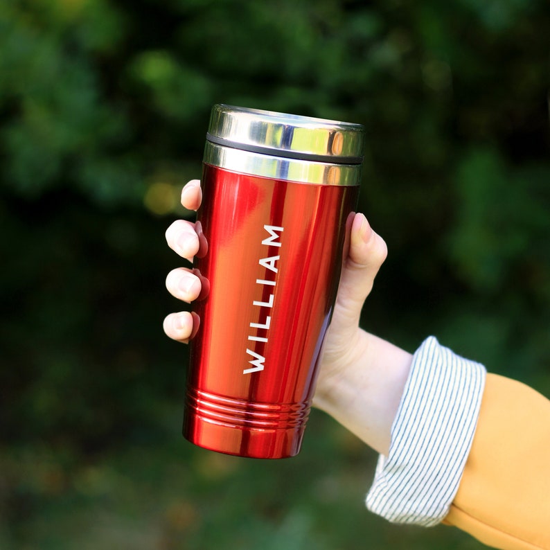 May include: Red travel mug with a silver lid and the name "WILLIAM" engraved on the side.
