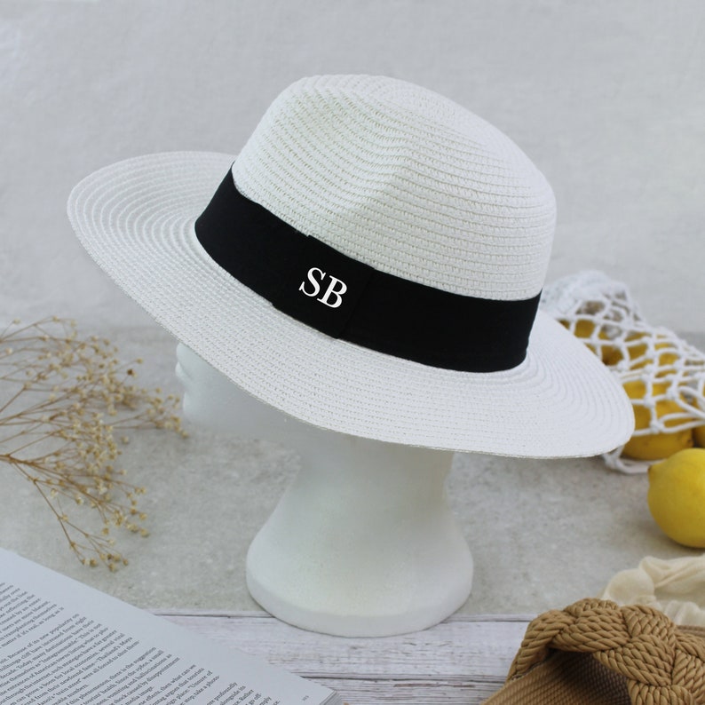 Peut inclure: Chapeau de paille blanc avec un ruban noir et les initiales "SB" brod&eacute;es sur le ruban.
