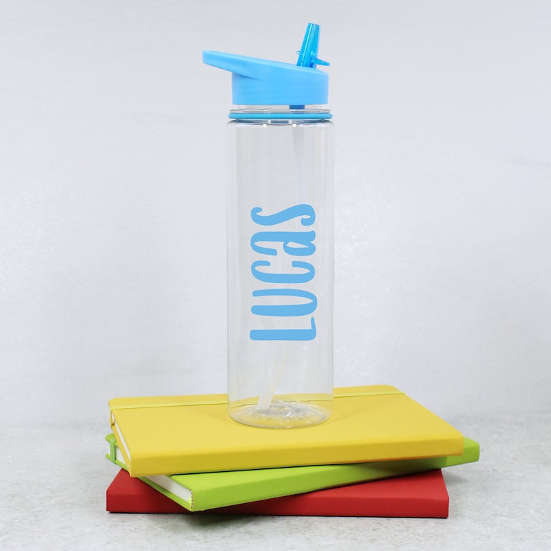 May include: A clear plastic water bottle with a blue lid and straw. The bottle has the name "Lucas" printed on it in blue lettering.