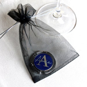 May include: A black mesh bag with a silver and blue personalized purse hook with the name "Amie" on it.