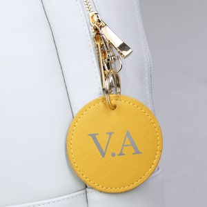 May include: A yellow leather keychain with the initials "V.A." in silver lettering.