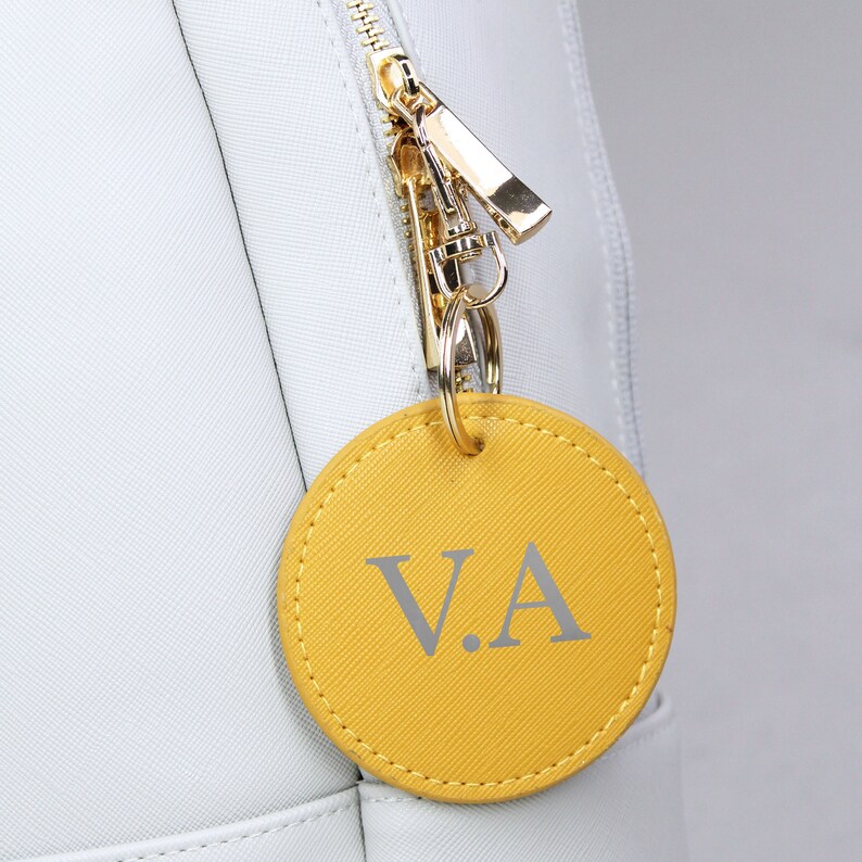 May include: A yellow leather keychain with the initials "V.A." in silver lettering.
