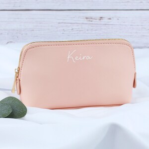 May include: A pale pink zippered pouch with a gold zipper and the name "Keira" written in white on the front.