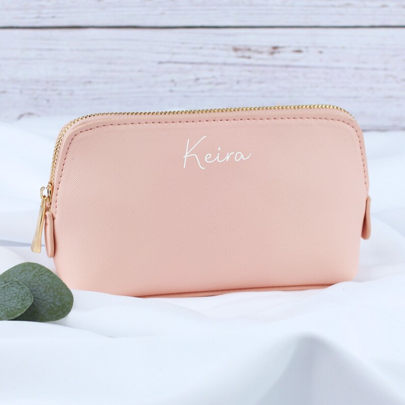 May include: A pale pink zippered pouch with a gold zipper and the name "Keira" written in white on the front.