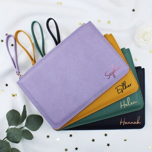 May include: Four personalised zippered pouches in different colours: lavender, mustard yellow, forest green, and black. The pouches have gold lettering with the names Sophia, Esther, Helen, and Hannah.