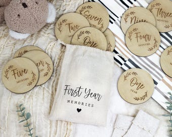 Può includere: Un set di dischi in legno per le tappe del bambino con una borsa di juta che dice "Primi ricordi dell'anno". I dischi presentano i numeri da uno a dodici, con le parole "mesi" o "anno" scritte su ogni disco. I dischi sono decorati con un semplice motivo floreale.