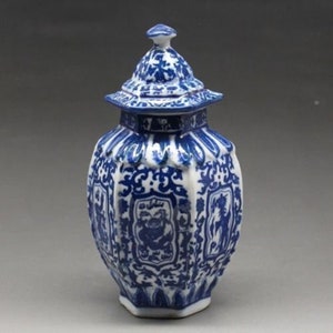 Könnte beinhalten: Eine blau-weiße Keramikvase mit Deckel. Die Vase hat eine sechseckige Form mit verzierten blauen Mustern und Illustrationen. Der Deckel ist ebenfalls blau und weiß, mit einem kleinen Knopf oben. Die Vase ist ein dekorativer Gegenstand.