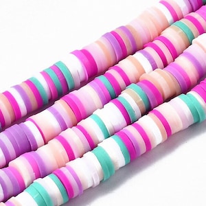 Peut inclure: Un brin de perles rondes empilées et colorées. Les perles sont en pâte polymère et sont dans des tons de rose, violet, blanc et vert.