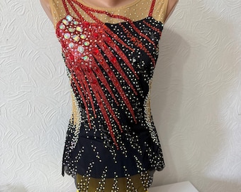 Può includere: Un body nero e rosso con un design decorativo. Il body presenta uno scollo in rete ed è impreziosito da strass. Il design include accenti rossi e una gonna nera. L'indumento è esposto su un manichino.