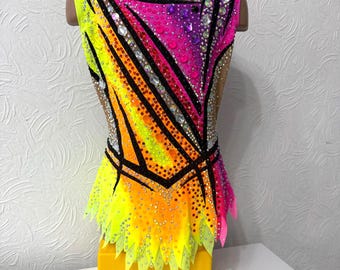 May include: A colorful leotard with a geometric design in shades of pink, yellow, orange, and black. The leotard is decorated with rhinestones and has a short skirt.