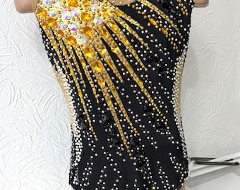 Può includere: Body nero con un designo oro e nero. Il body è ricoperto di strass e ha un pannello in rete sul retro.