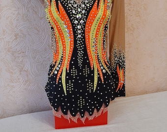 Può includere: Un body nero con una manica lunga su un lato. Il body è decorato con fiamme arancioni, gialle e nere e strass.