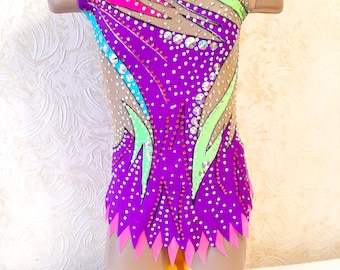 Peut inclure: Un justaucorps violet avec un motif abstrait coloré et des strass. Le justaucorps a un col rond et est sans manches.