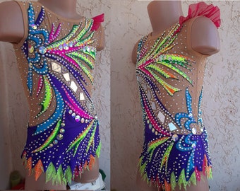 May include: A colorful leotard with a purple skirt and rhinestones. The leotard has a rainbow design with green, blue, pink, and orange accents.