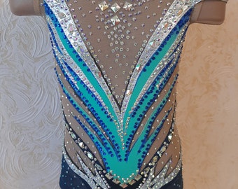 May include: A black, blue, and turquoise leotard with rhinestones and a mesh design. The leotard has a scoop neck and short sleeves.
