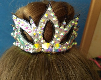May include: A silver crown hair accessory with rhinestones, designed in a flame shape.