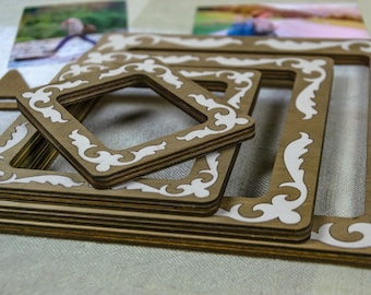 May include: A set of nested square frames made of brown wood with white decorative filigree patterns along the borders. The frames are stacked on top of each other, showing varying sizes with a consistent cutout design on each wooden piece.