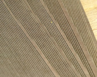 May include: A set of overlapping rectangular sheets featuring a fine, uniform grid of small perforations. The material is a muted, earthy taupe colour, displaying a consistent texture across the surface of each individual sheet in the stack.